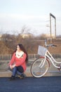 The girl sits next to a parked bike. Rest on the spring cycle Royalty Free Stock Photo