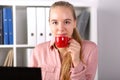Girl sits office front computer and drinks coffee
