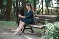 A girl sits on a park bench and looks at her phone, waiting for a man on a date Royalty Free Stock Photo