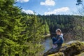 A girl sits in a park near a recreation area in nature. A girl looks from a height at the river.A young girl stands near a cliff,