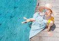 Girl sits on the pier near the parked boats on the Mediterranean coast. Vacation and travel concept