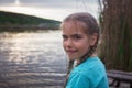 Girl sits on pontoon bridge at lake and enjoys warm sunny evening, happy summertime, countryside Royalty Free Stock Photo