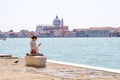 A girl sits reading an e book on the waterfront in Venice