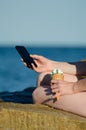 A girl sits on a rock near the sea with a smartphone and ice cream Royalty Free Stock Photo