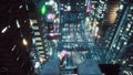 A girl sits on the roof of a skyscraper, dangles her legs and admires the neon city of the future. View of an future