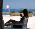 The girl sits in the shade and drinks a cocktail