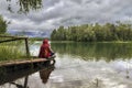 The girl sits on the shore of the lake and fishes. Royalty Free Stock Photo