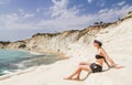 A girl sits on a slope of white cliff called