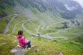 Girl sits on stone enjoying wonderful mountain scenery. Transfagarashan Highway