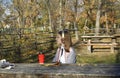 a girl sits at a table in an autumn park, headphones are on her head Royalty Free Stock Photo