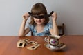 A girl sits at a table and plays with film