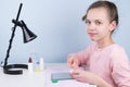 The girl sits at the table and puts on a contact lens to improve vision