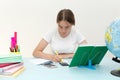 A girl sits at a table and writes homework in a notebook. Overwrites from a book. Student.student. On the table are Royalty Free Stock Photo