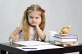 The girl writes on a piece of paper sitting at the table in the image of the writer Royalty Free Stock Photo