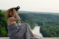 Girl sits and takes pictures against the background of forest and meandering river Royalty Free Stock Photo