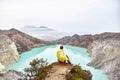 The girl sits on top of the volcano and looks at the lake in the crater Royalty Free Stock Photo