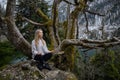 Girl sits on a tree and meditates near lake Ritsa in Abkhazia Royalty Free Stock Photo