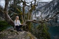 Girl sits on a tree and meditates near lake Ritsa in Abkhazia Royalty Free Stock Photo