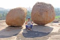 A girl sits between two large stones in Hampi. Large stones Hampi on the side of the village of Anegundi and Virupapur Gaddi.