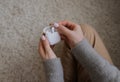 The girl sits on a white carpet opens a white case with headphones. View from above. Royalty Free Stock Photo