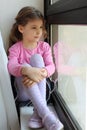 Girl sits on windowsill and looks out window Royalty Free Stock Photo