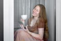 Girl sits on a windowsill by the window.