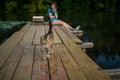 A girl sits on a wooden pier and watches a cat walking on the boards Royalty Free Stock Photo