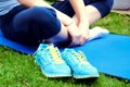 Girl sitthing on a yoga mat crosslegged with her blue sneakers o