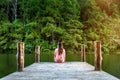 Girl sitting alone on a the wooden bridge on the lake. Pang Ung, Thailand