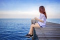 Girl sitting alone on a the wooden bridge on the sea.