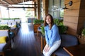 Girl sitting in arm chair at cafe near room plants and table. Royalty Free Stock Photo