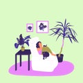 Girl is sitting in armchair and reading book with a cat in cosy room with potted tropical plants.