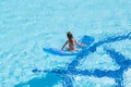 A girl sitting back on mattress in the pool Royalty Free Stock Photo