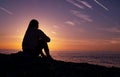 A girl is sitting on the beach watching the sunset. Royalty Free Stock Photo