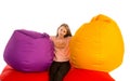 Girl sitting between beanbag chairs on red beanbag sofa Royalty Free Stock Photo