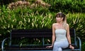 The girl is sitting on a bench in a beautiful garden.