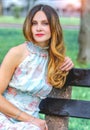 A girl sitting on a bench in the park. Light summer dress, floral print Royalty Free Stock Photo