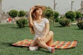 A Girl Is Sitting On The Blanket On The Grass In The Park With Crossed Legs. Royalty Free Stock Photo