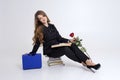 Adult Girl Sitting On Books Sniffing Red Rose White Background Space For Text Black High Heels Blue Suitcase For Study