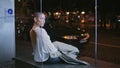 Girl sitting bus stop late evening. Short hair woman waiting public transport Royalty Free Stock Photo