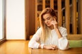 A girl is sitting in a cafe and using a smartphone