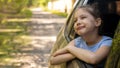 the girl is sitting in the car in a car seat and looks out the window at nature. A small child travels by car. Safety of Royalty Free Stock Photo