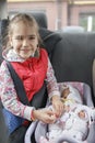 Girl sitting in car seats and playing with doll which also in car seat, child transportation safety Royalty Free Stock Photo