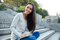 Girl sitting on the city stairs with pencil and notepad outdoors