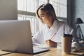 Girl sitting concentrated at laptop and studying remotely. Student using online opprotunities for distant education.