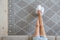 Girl sitting on the couch on her feet slippers on the carpet