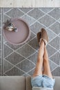 Girl sitting on the couch on her feet slippers on the carpet