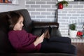Girl sitting on the couch and holding a cell phone and tablet Royalty Free Stock Photo