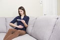 Girl sitting on a couch at home while reading the results of her recent pregnancy test Royalty Free Stock Photo