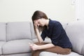 Girl sitting on a couch at home while reading the results of her recent pregnancy test Royalty Free Stock Photo